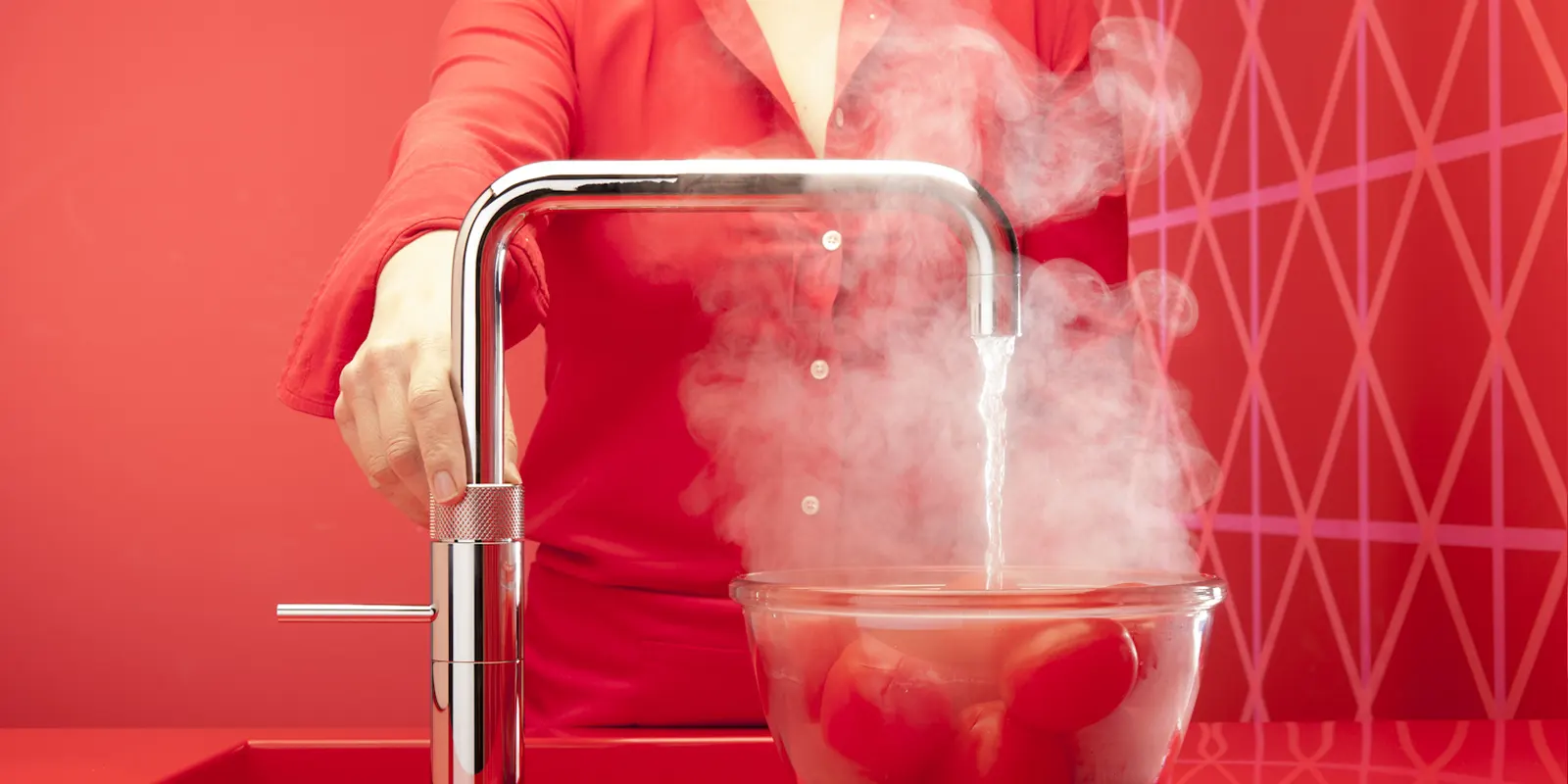 Boiling water flowing from a modern boiling water tap into a pan, symbolizing vulnerability to limescale buildup